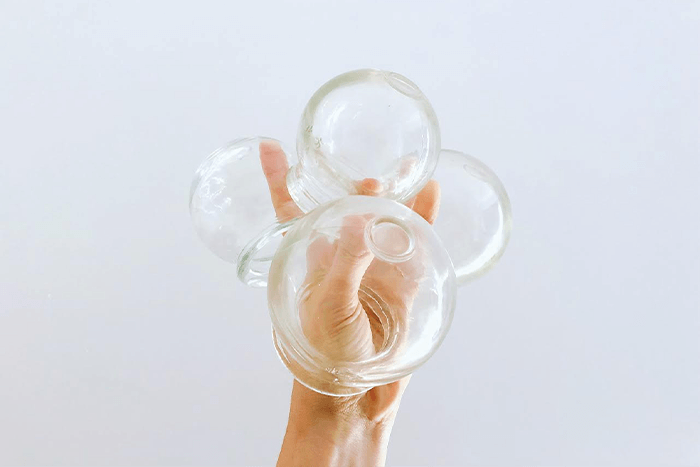 Woman holding up cups used for a cupping massage for relaxation in Brisbane